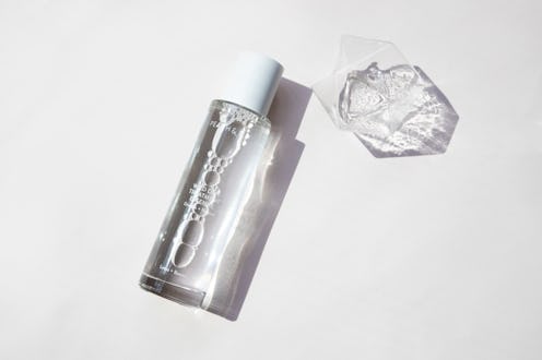 Bottle of Wild Dew Treatment Essence next to a glass of water