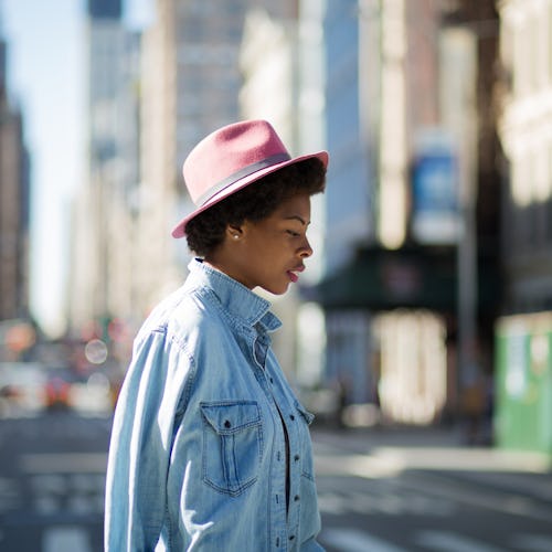 A woman who is single and happy walking  in a blue denim shirt and a pink hat