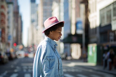 A woman who is single and happy walking  in a blue denim shirt and a pink hat