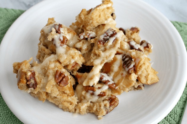 white plate with a serving of baked french toast with icing and walnuts