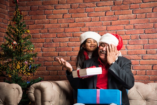 Grandfather opening Christmas presents with his granddaughter