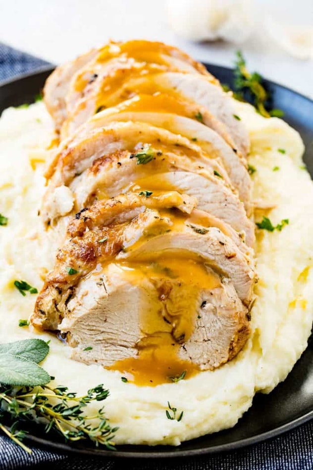sliced turkey laying on bed of mashed potatoes with gravy on top