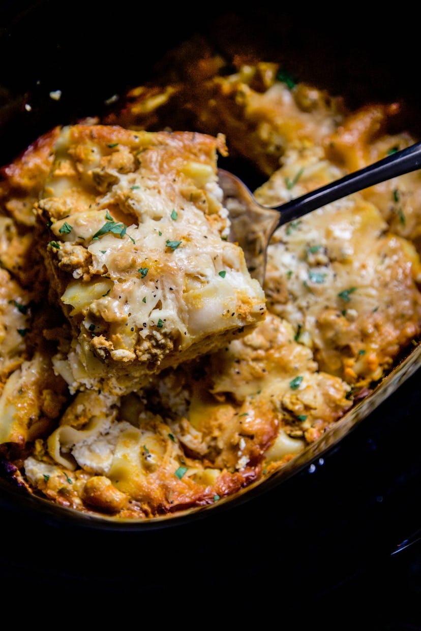 A fork taking out a piece of lasagna from a slow cooker