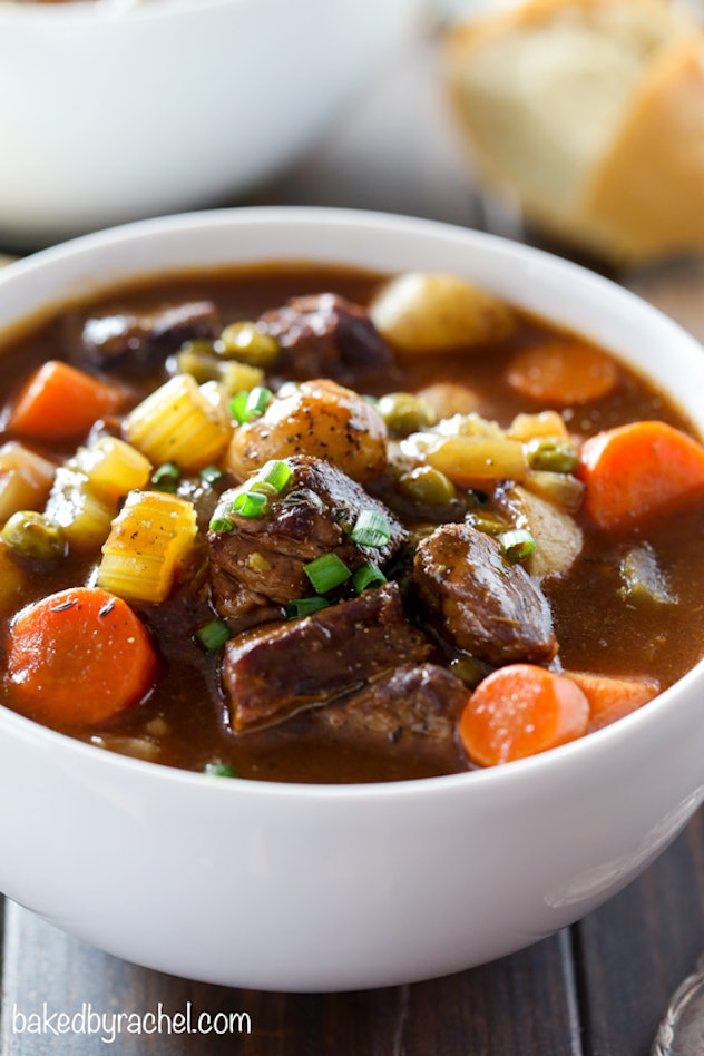 A white bowl full of beef stew with chunks of carrots, and potatoes, celery, and beef