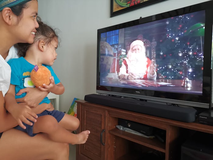 Jam Kotenko holding her child while their watching a television show with Santa in it