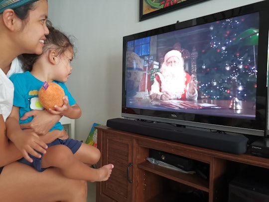 Jam Kotenko holding her child while their watching a television show with Santa in it