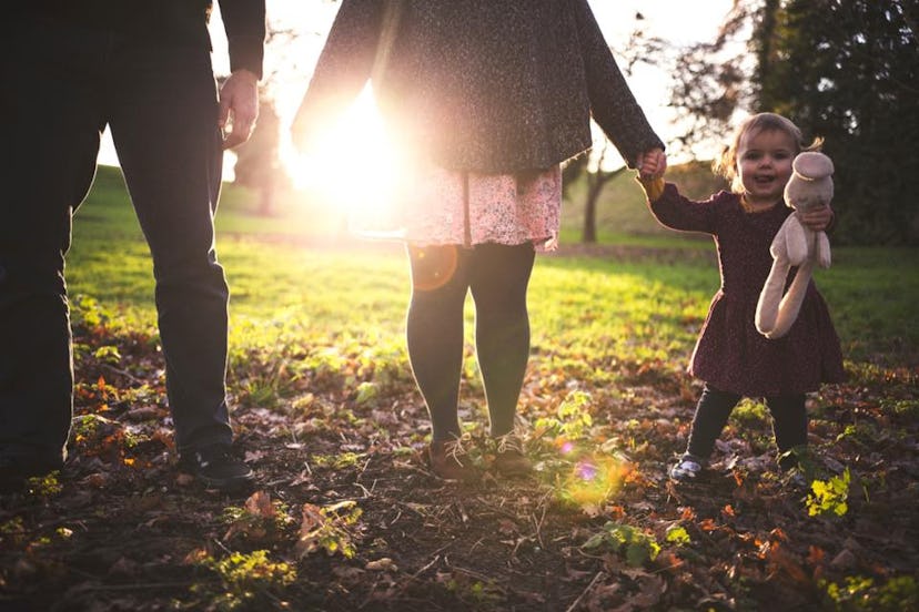 A man and woman, who are ttc a second child, walking with their first child in nature 