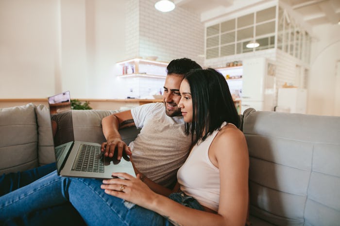 A couple on their couch watching a steamy movie on Hulu on their laptop