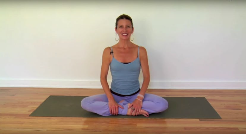 A woman sitting on a yoga mat in spinal flexes pose