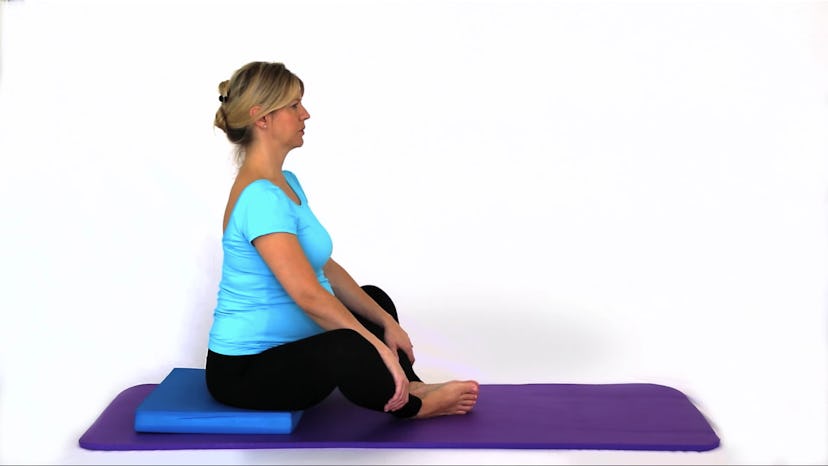 A woman sitting on a yoga mat in a tailor pose
