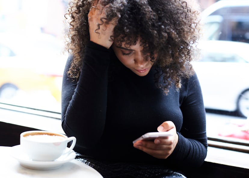 A woman looking at her phone worried