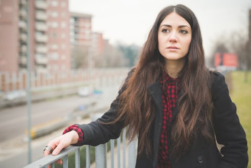 A woman leaned on a fence and looking away as she thinks of common types of cancer that young women ...