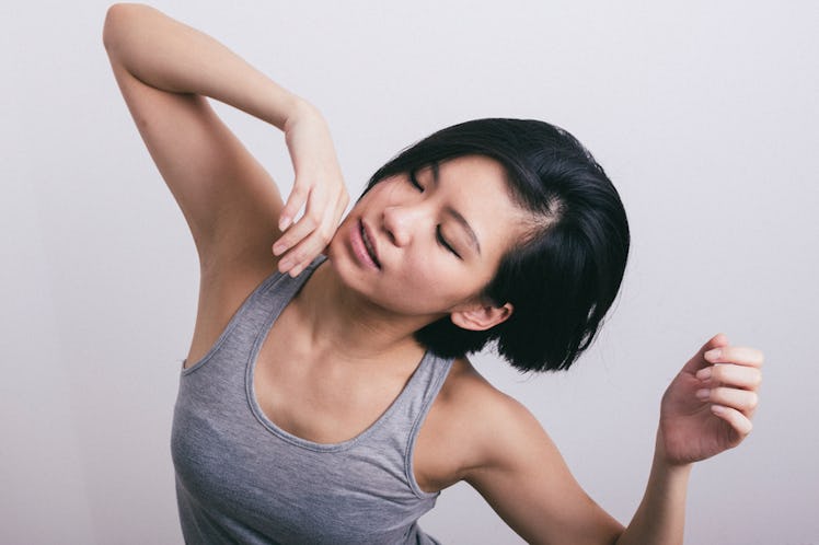 A black-haired woman in a grey tank top during her stretching routine