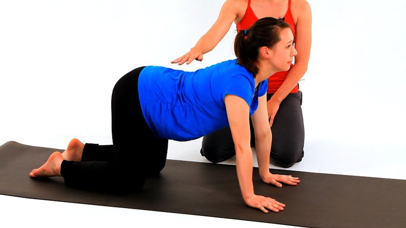 Pregnant woman doing yoga cat cow pose.
