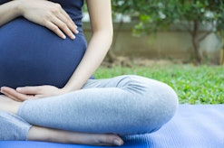 A pregnant mother sitting in a yoga pose that induces labor