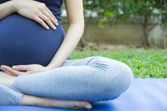 A pregnant mother sitting in a yoga pose that induces labor