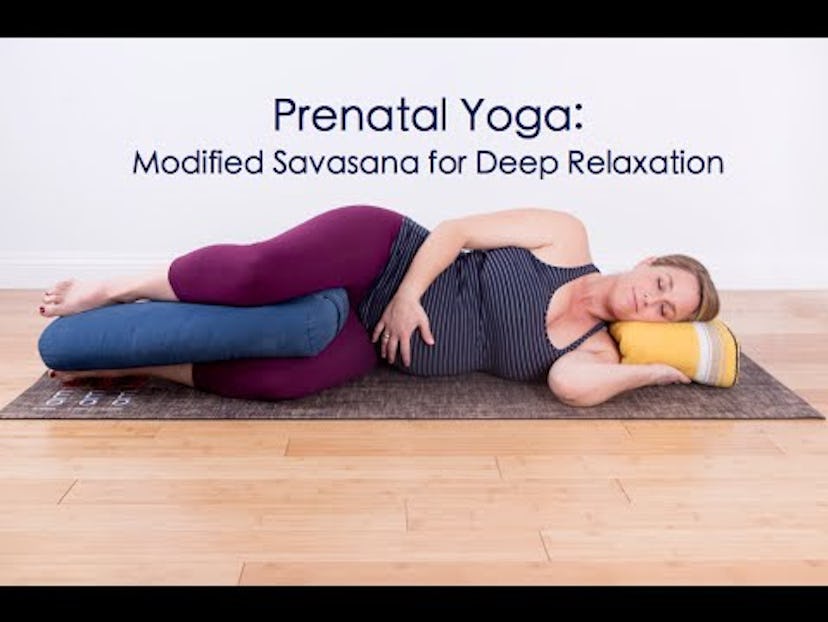 A pregnant woman lying on a yoga mat in savasana pose