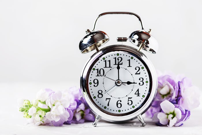 An alarm clock surrounded by flowers, representing daylight saving time