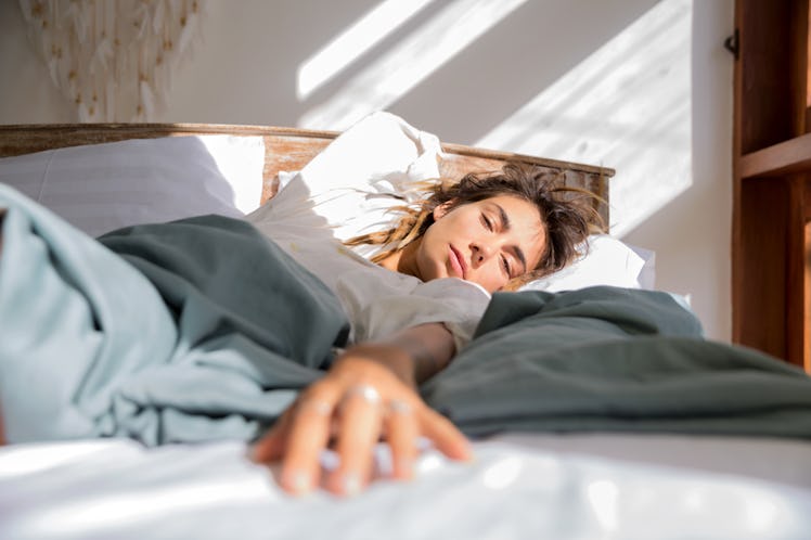 A sun-kissed woman in bed in the best sleeping position for her posture during day time