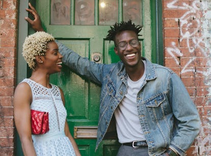 A young couple stands outside talking and laughing.