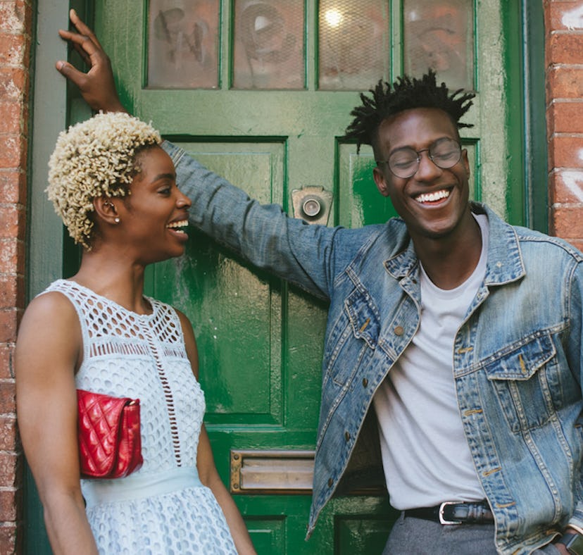 A young couple stands outside talking and laughing.