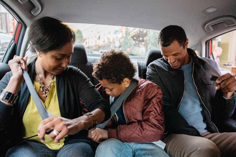 Two parents buckle themselves and their child up in the back seat of an uber using uber health