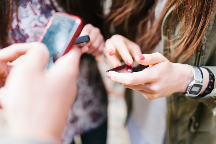 Three young women staring at their mobile phone screens