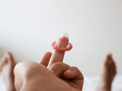 A person holding a condom on its finger
