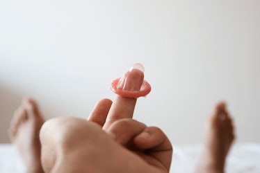 A person holding a condom on its finger