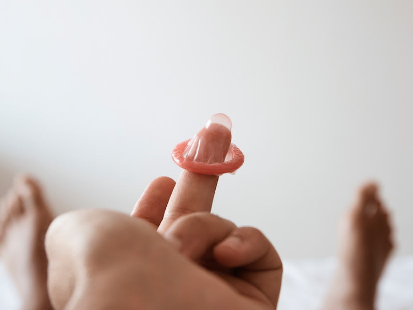 A person holding a condom on its finger