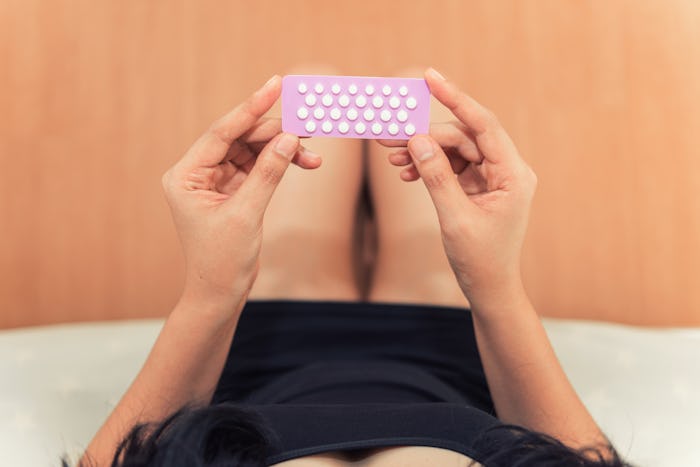woman's hands holding birth control pills