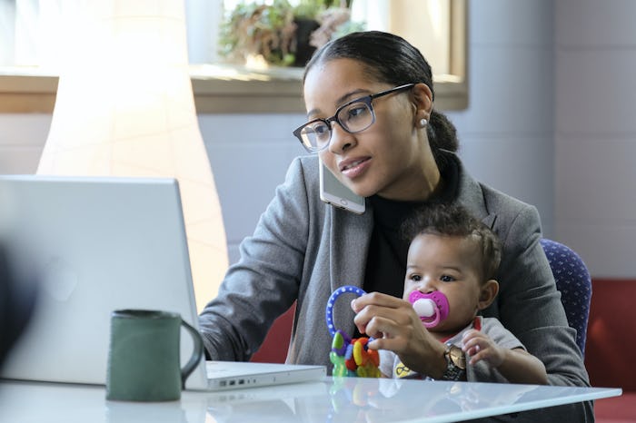 A working mom using her laptop and phone with her baby in her lap