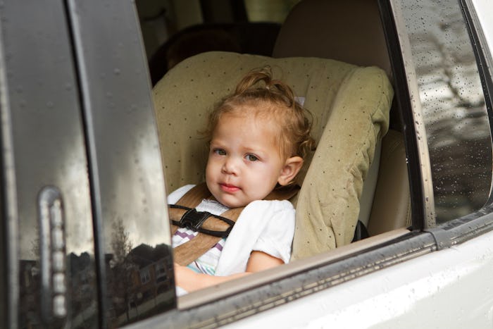 Toddler girl sitting in a car seat next to an opened window