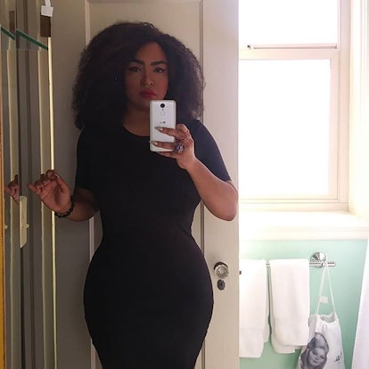 Zahira Kelly-Cabrera in a form fitting black dress taking a camera selfie in her bathroom