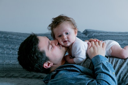 The dad kissing his little child while laying in the bed