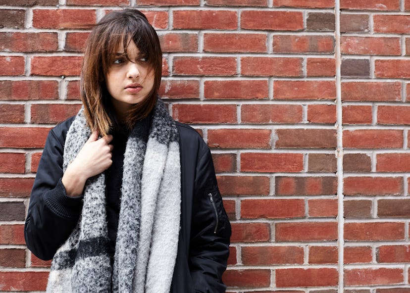 A woman with dementia and memory loss standing leaned against a brick wall