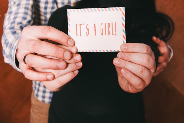 Parents holding a sign "It's a girl"