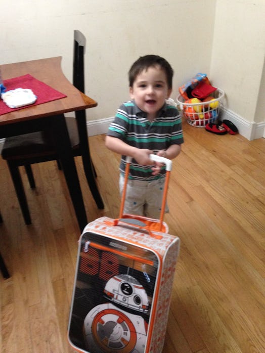 A young child pulls a wheelie suitcase