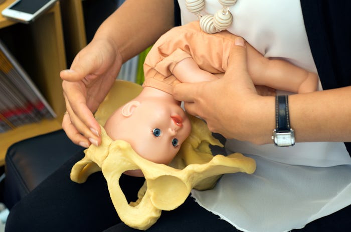 A Med Student using a doll of a baby and a model pelvis to show what giving birth is like