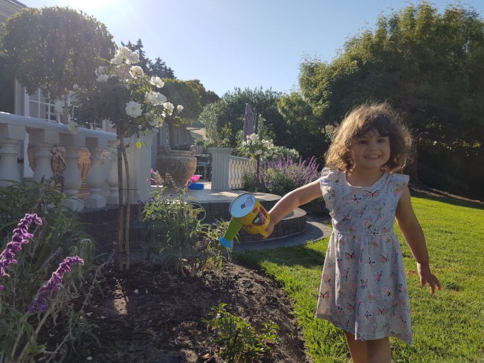 A little girl named Sophia watering plants in a floral dress