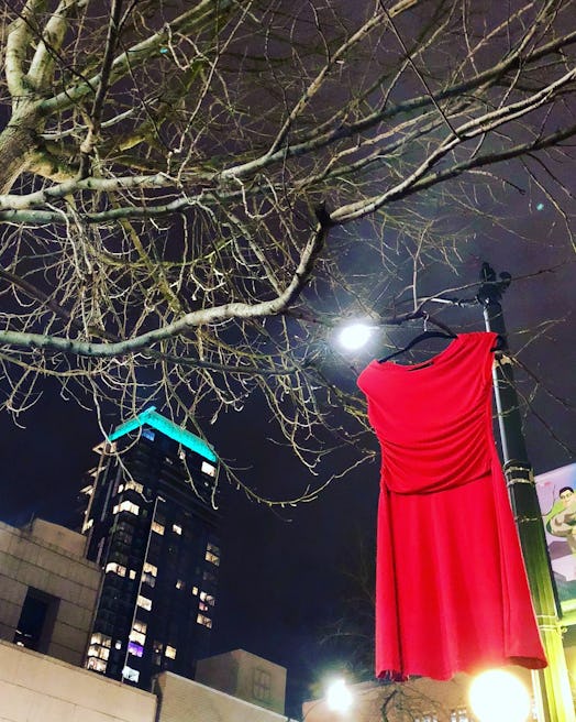 A red dress hanged on a tree next to a lamppost