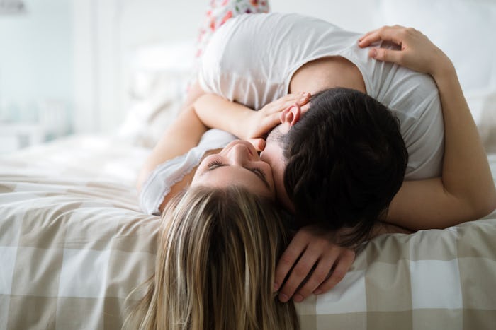A couple kissing while lying in a bed