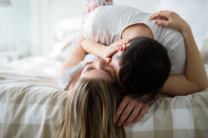 A couple kissing while lying in a bed
