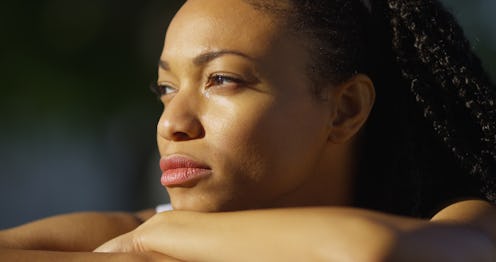 A sunkissed sad woman looking through the window