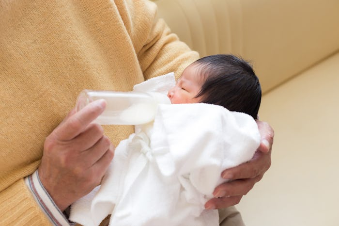 A parent feeding a newborn with breastmilk from a bottle