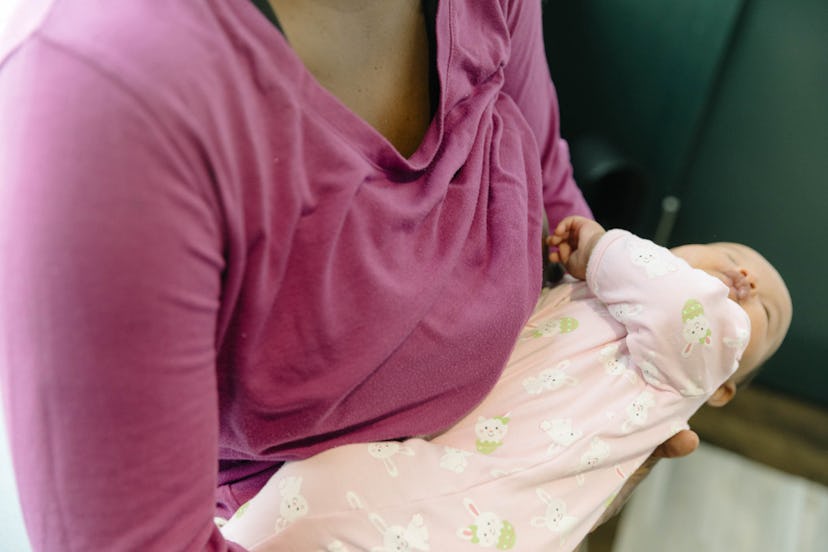 A mother in a purple top holding her newborn baby 