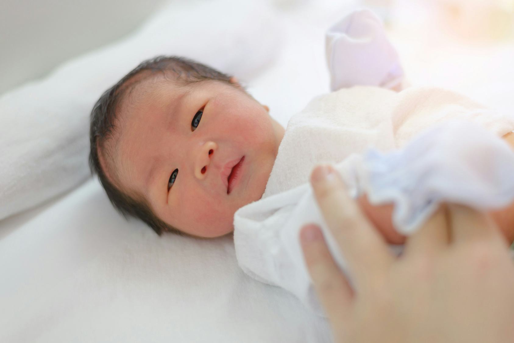 A baby with a floral name lying down on the bed 
