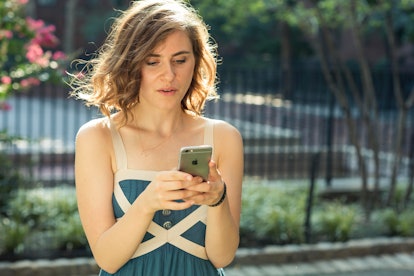 A woman in a blue dress using her phone and stressing out about her everyday activities