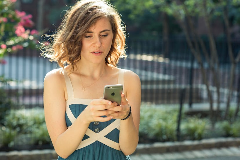 A woman in a blue dress using her phone and stressing out about her everyday activities