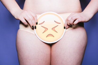 A woman in panties holds an emoji cut out in front of her